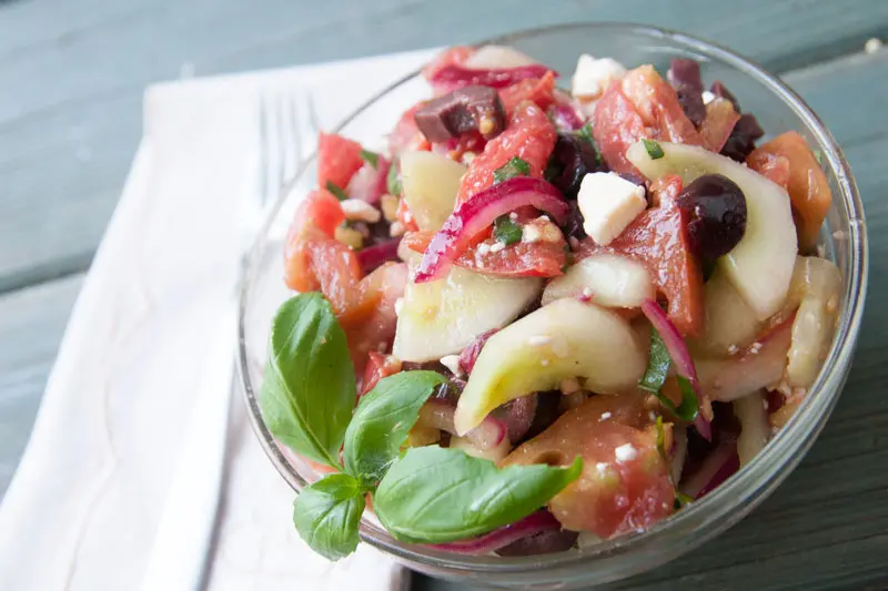 This tangy cucumber tomato salad is packed with flavor and freshness! Kalamata olives, feta cheese, and red onions add interest without stealing the show from the crisp cucumber and juicy tomatoes. | www.pinchmeimeating.com