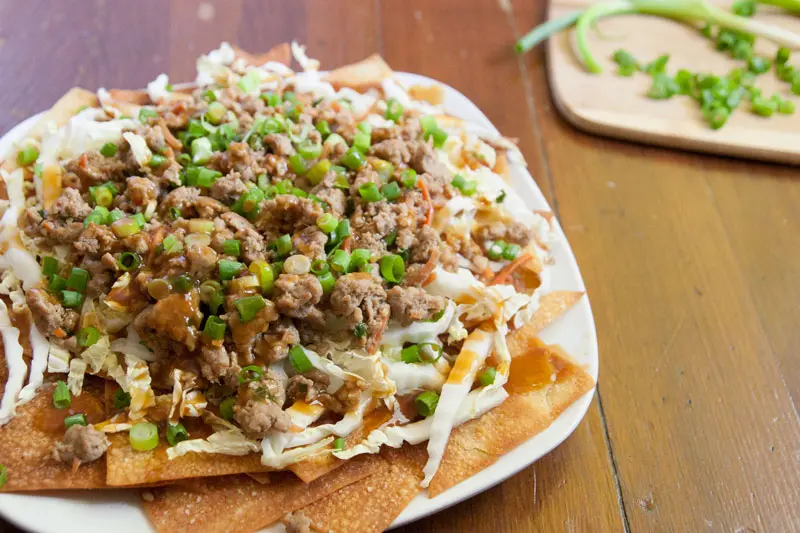 Potsticker Nachos with Baked Sesame Ginger Wonton Chips | Enjoy juicy, gingery pork gyoza filling in a fun, easy-to-share format. These Asian-inspired nachos are sure to be a hit! | www.pinchmeimeating.com