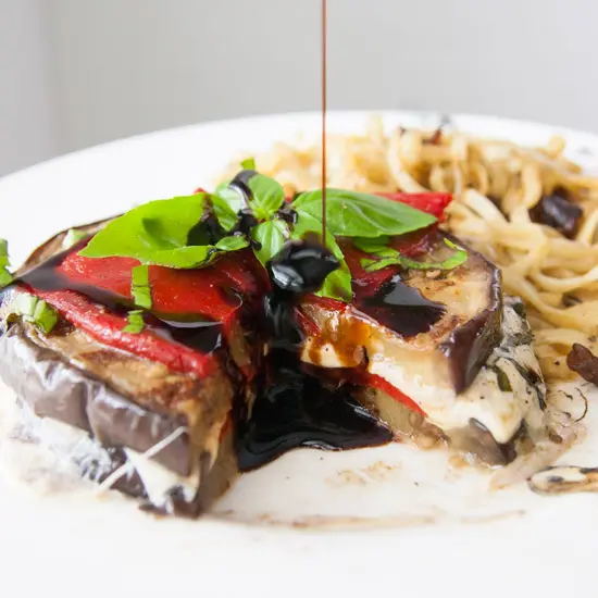 Vegetarian and grain-free, these grilled balsamic eggplant stacks are full of oh-so-melty mozzarella cheese, smoky roasted red peppers, and basil, and are perfect for a light dinner! | www.pinchmeimeating.com