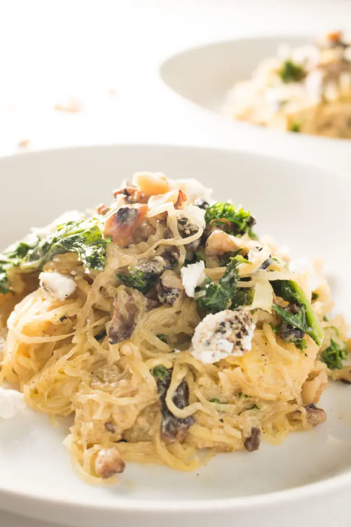 Spaghetti squash with mushrooms, walnuts, kale, and a nutmeg cream sauce is a naturally sweet, earthy dish that's simple to make, low carb, and gluten free. Great for Meatless Mondays or Meatless Fridays! There are also some great tips for the best way to cook a spaghetti squash! | www.pinchmeimeating.com