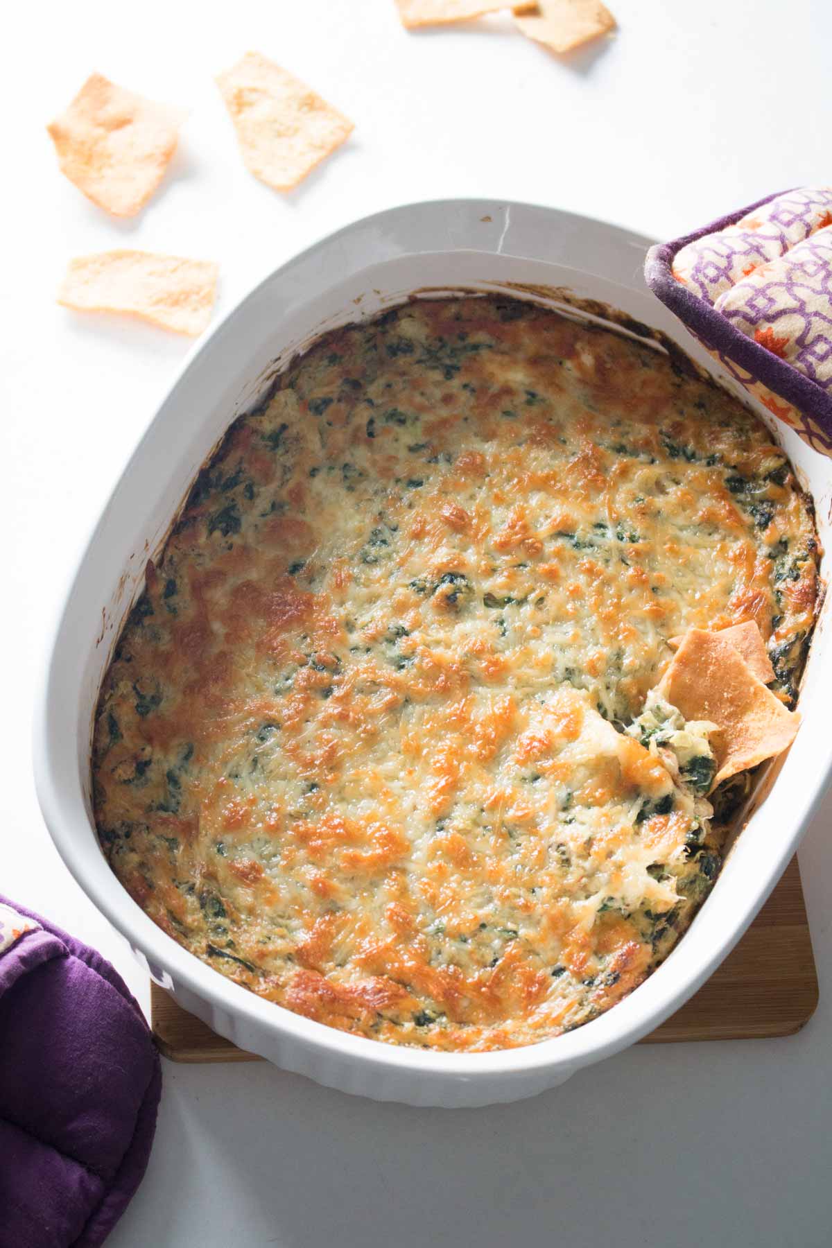 Overhead view of baked spinach, artichoke, and crab dip in white casserole dish