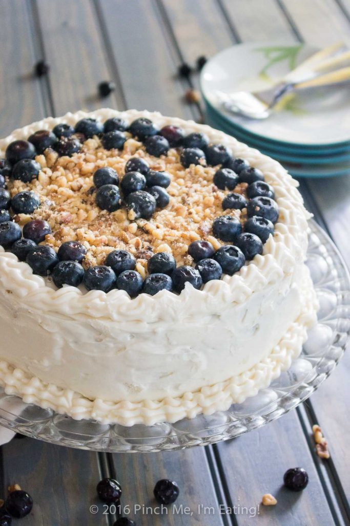 Blueberry spice cake with walnuts is layered with gooey blueberry jam and cream cheese frosting, and topped with walnuts and fresh berries for the perfect bite. A great cake for spring! | www.pinchmeimeating.com