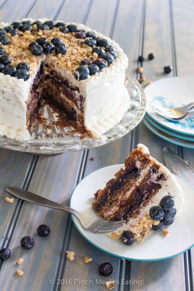 Blueberry spice cake with walnuts is layered with gooey blueberry jam and cream cheese frosting, and topped with walnuts and fresh berries for the perfect bite. A great cake for spring! | www.pinchmeimeating.com