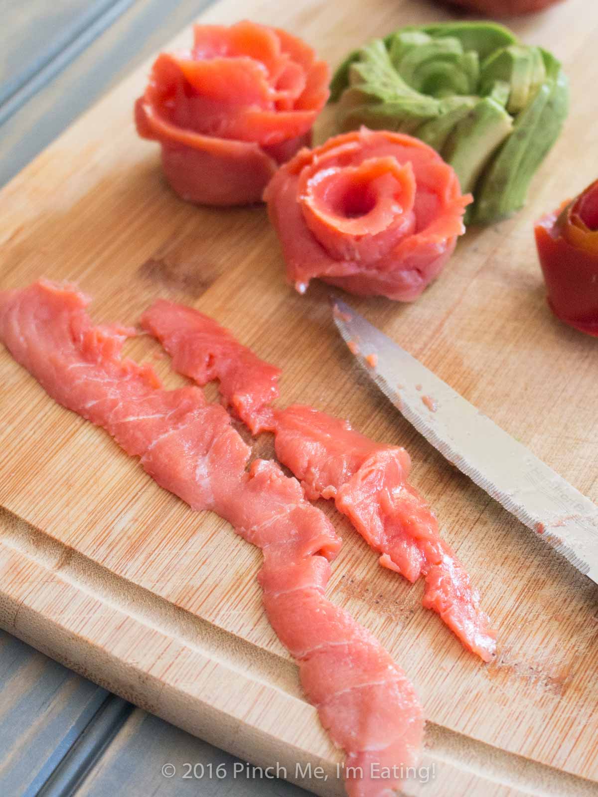 Smoked salmon strips on a wooden cutting board.