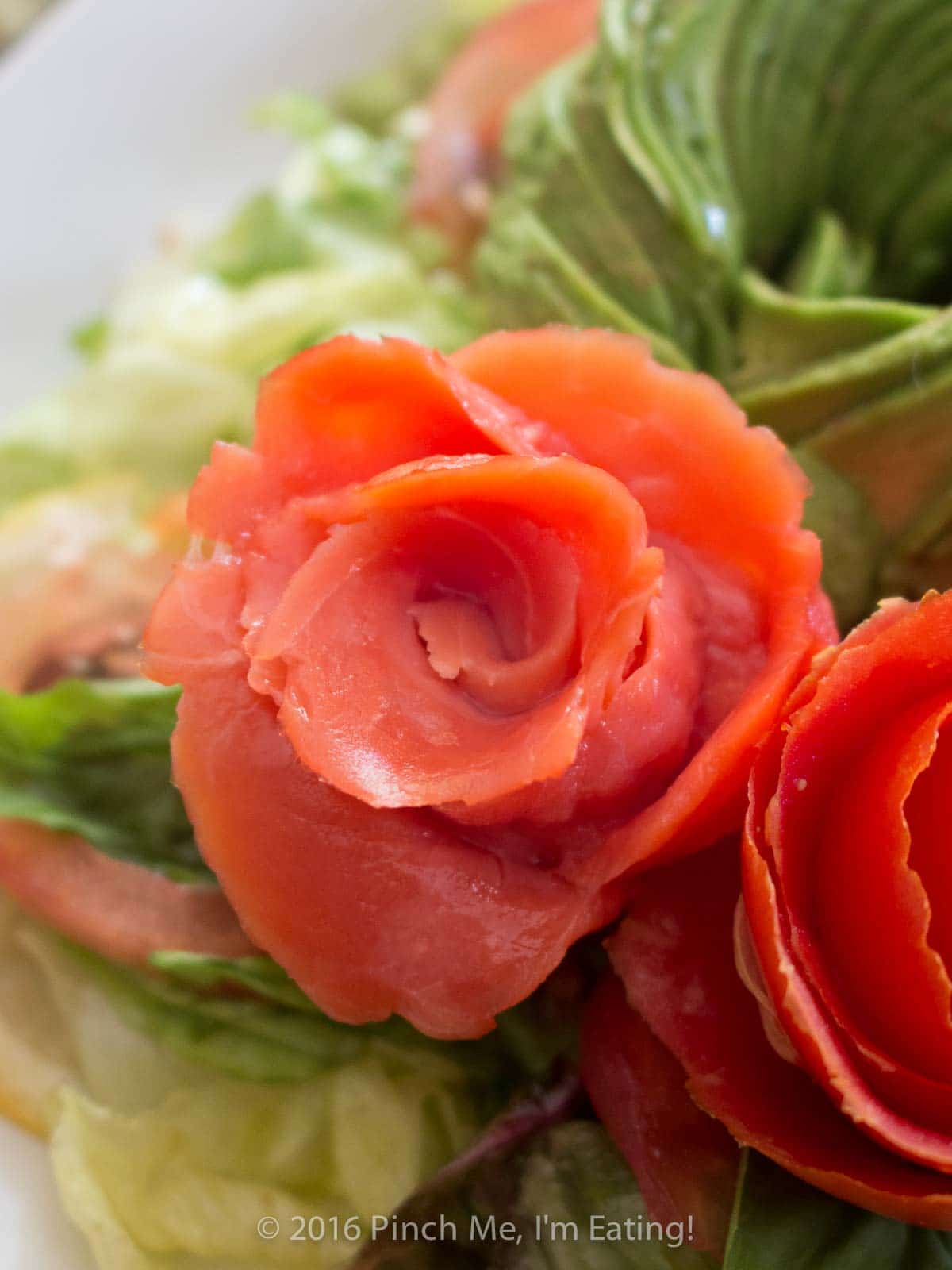Closeup of an edible rose made from spiraled smoked salmon strips.