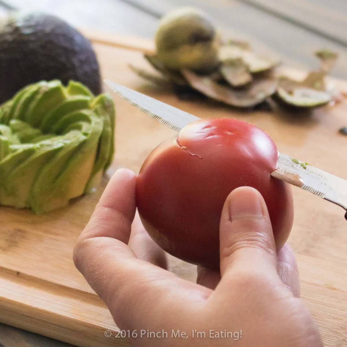 Process shot of making an edible tomato rose by slicing the bottom of the tomato most of the way through.