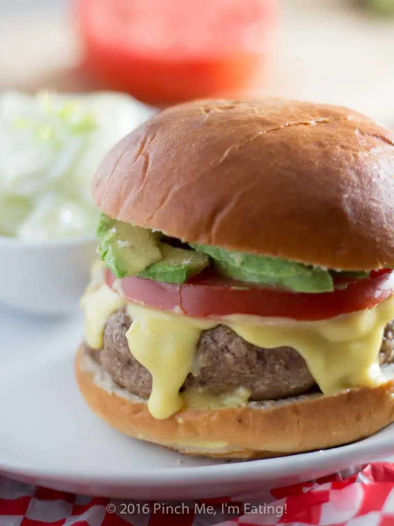 This juicy, aromatic turkey burger topped with tomato, avocado, and Hollandaise sauce will make you feel like you're relaxing at an outdoor cafe! | www.pinchmeimeating.com