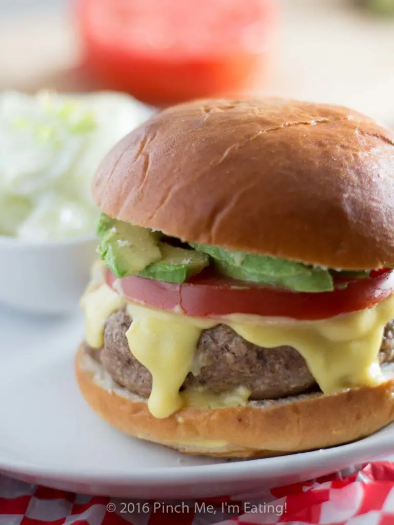 These juicy, aromatic gourmet turkey burgers topped with tomato, avocado, and Hollandaise sauce will make you feel like you're relaxing at an outdoor cafe! | www.pinchmeimeating.com