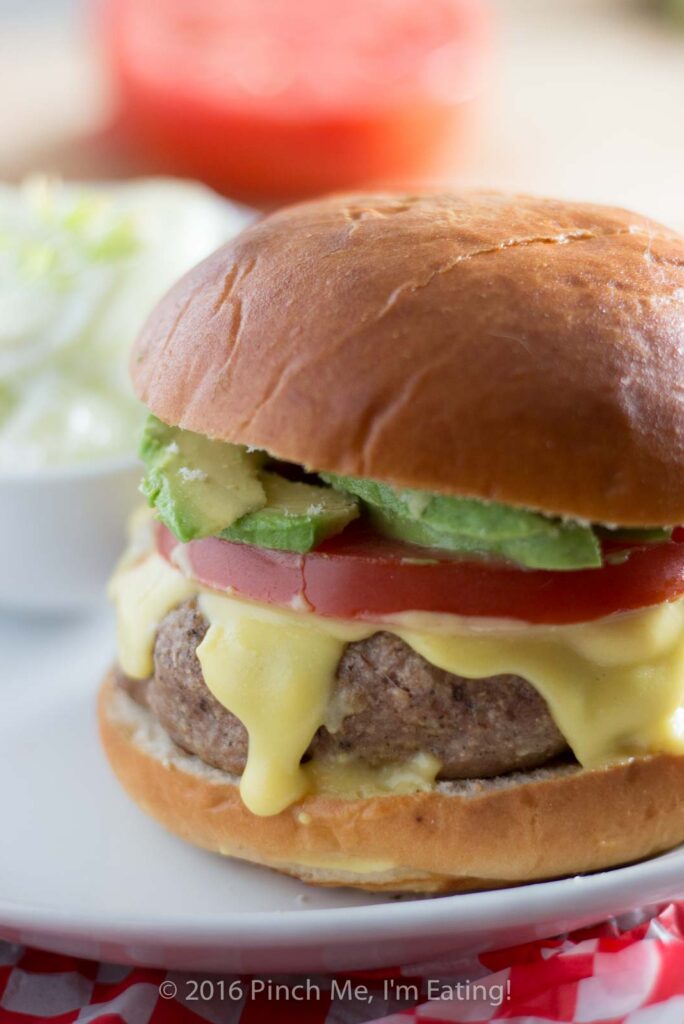 This juicy, aromatic gourmet turkey burger topped with tomato, avocado, and Hollandaise sauce will make you feel like you're relaxing at an outdoor cafe! | www.pinchmeimeating.com