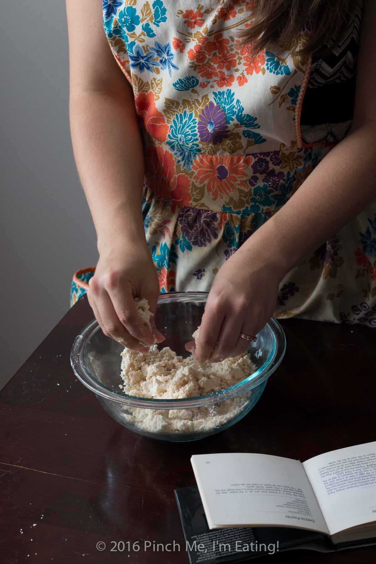 Woman making pastry dough in glass bowl.