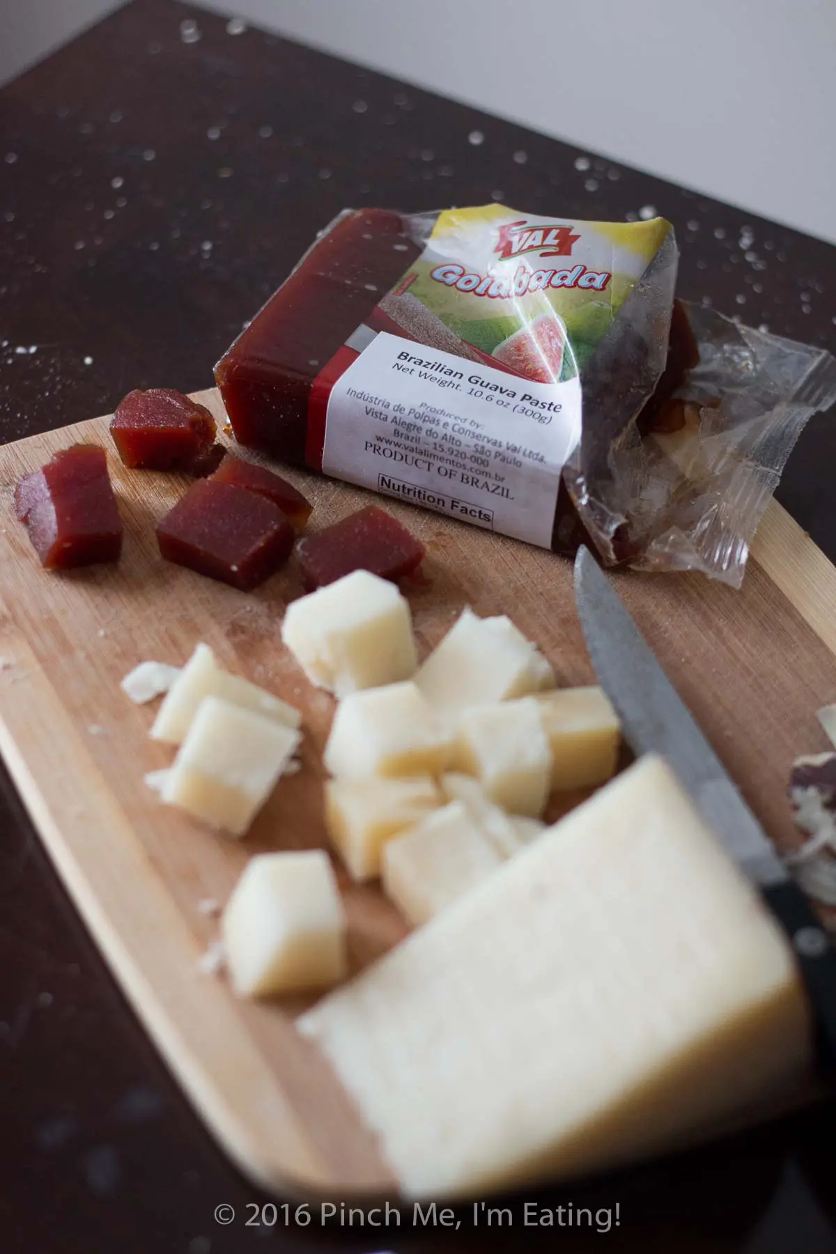 Diced guava paste and manchego cheese on a wooden cutting board.