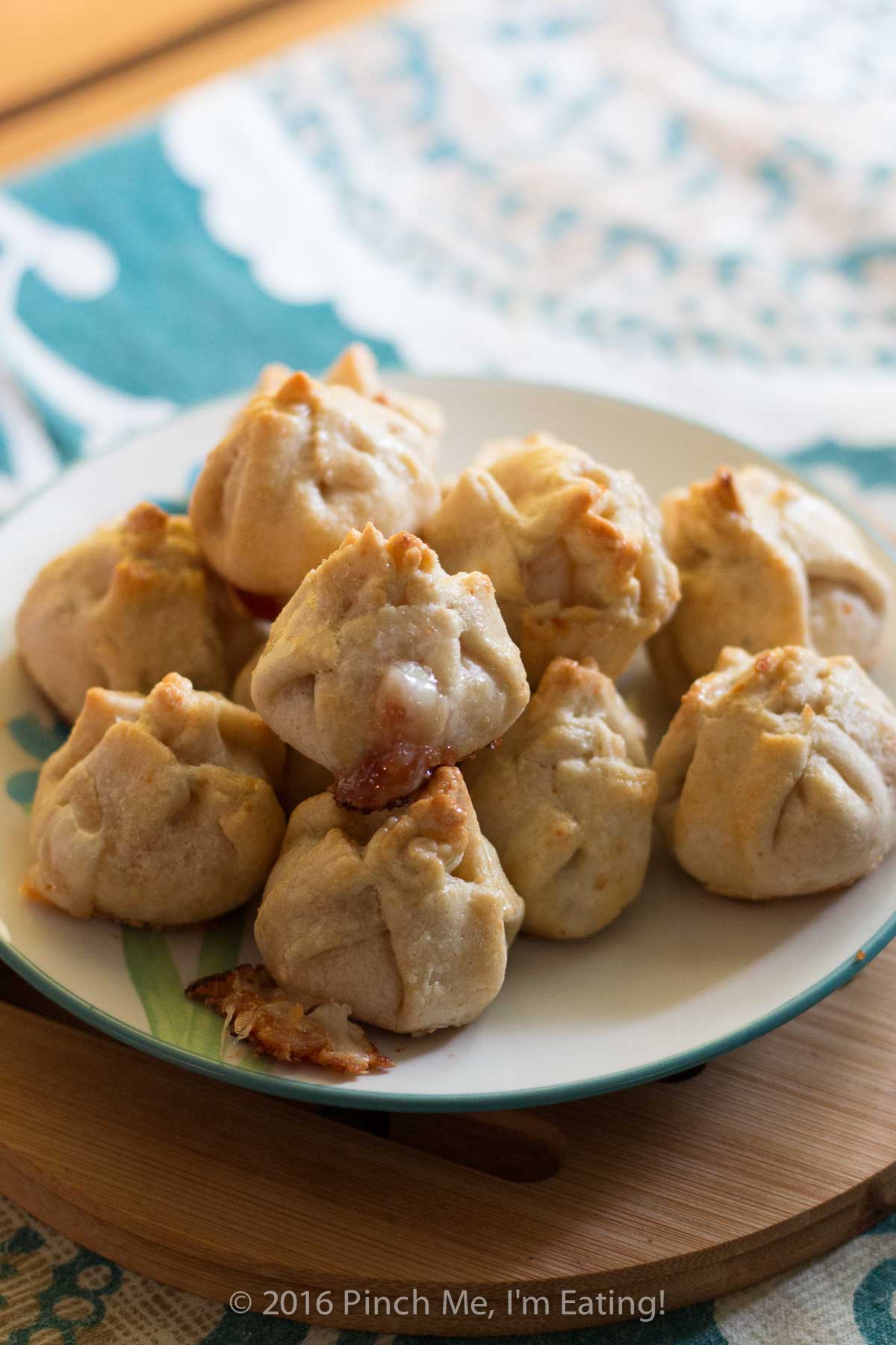 Guava and manchego cheese pastry bites on a white plate on a wooden trivet.