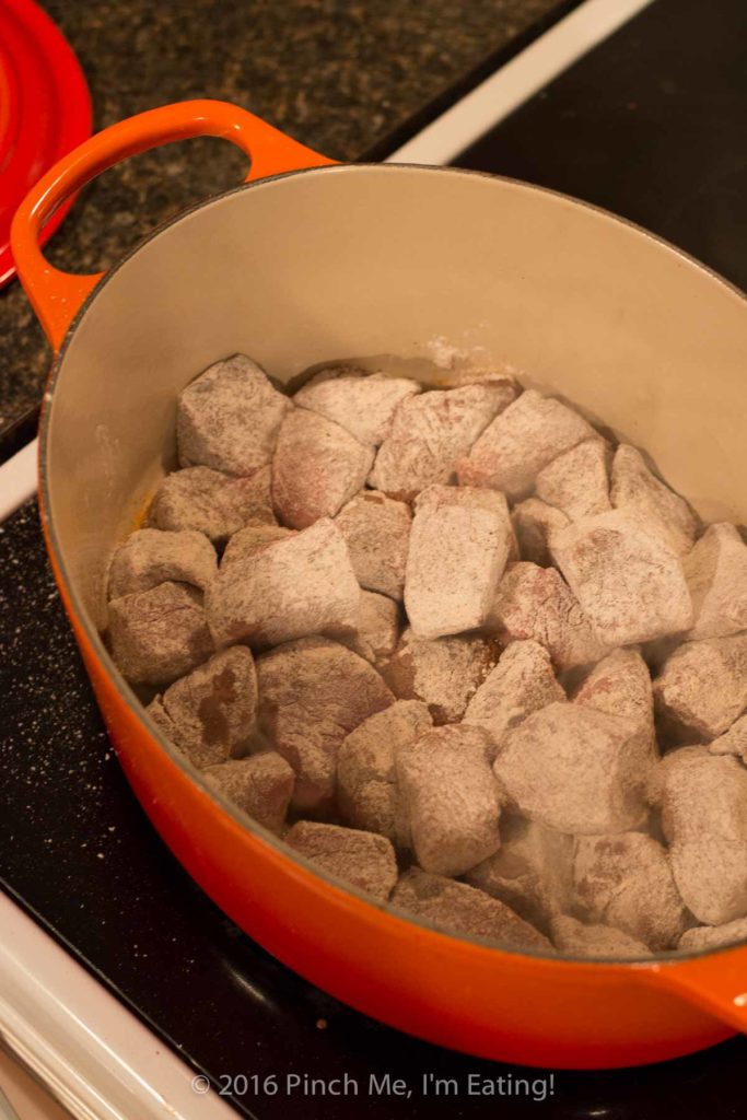 Meat for stove top beef stew coated in flour in Dutch Oven
