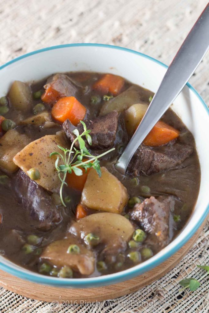 Close up of stove top beef stew with red wine with sprig of thyme on top