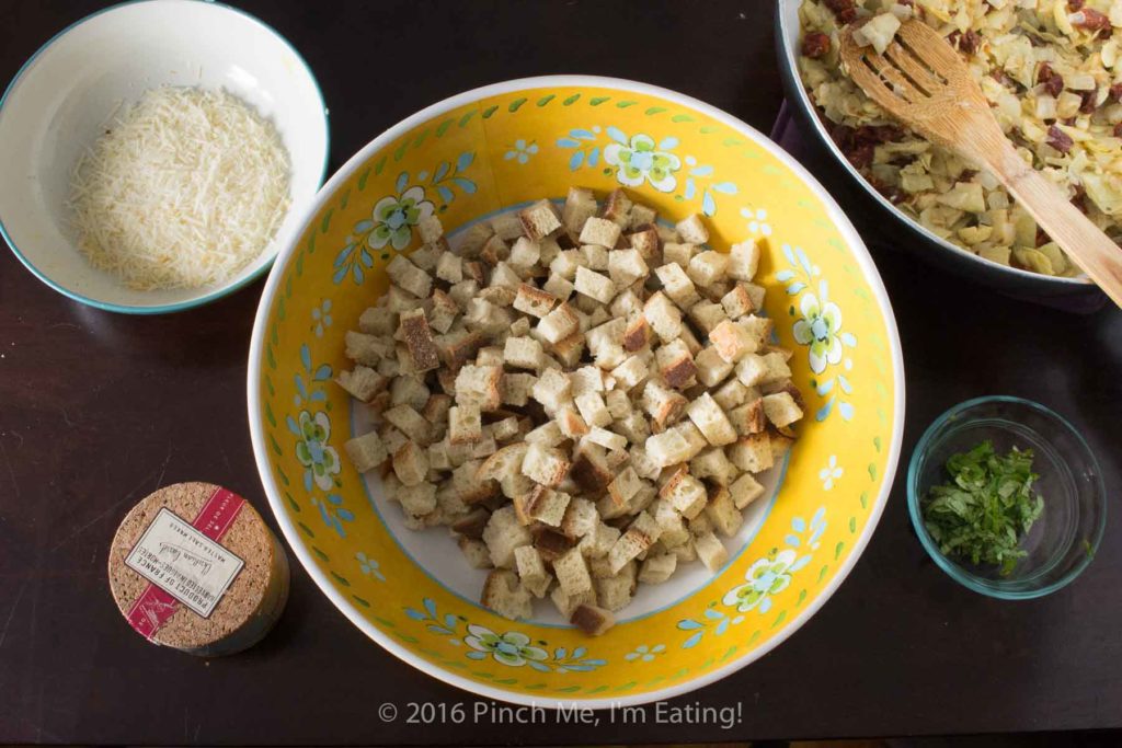 Sourdough sun-dried tomato artichoke stuffing with parmesan is a unique and delicious take on a holiday staple! This recipe is sure to be a crowd-pleaser this Thanksgiving or Christmas! | www.pinchmeimeating.com