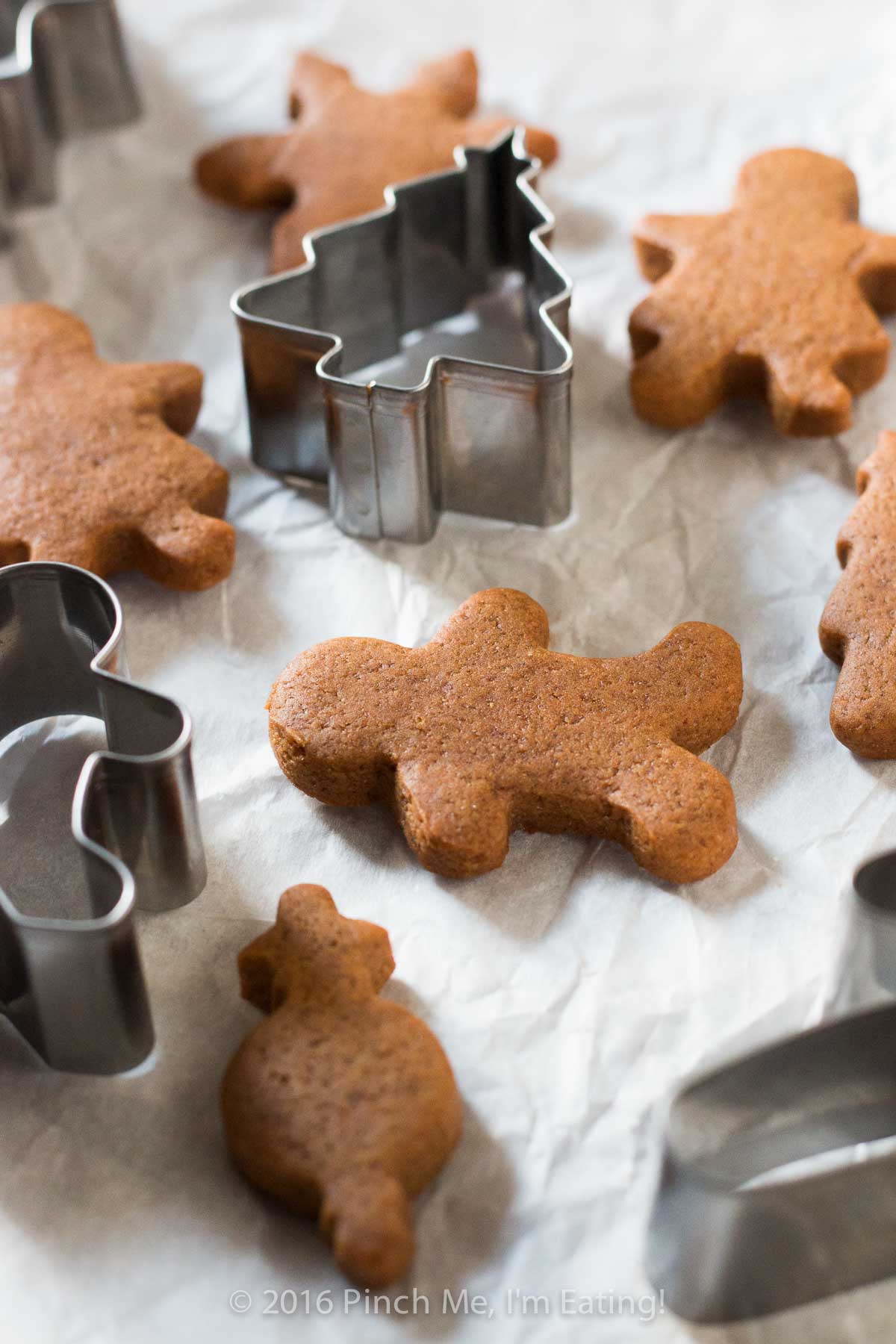 Chewy gingerbread cutout cookies on parchment paper with cookie cutters