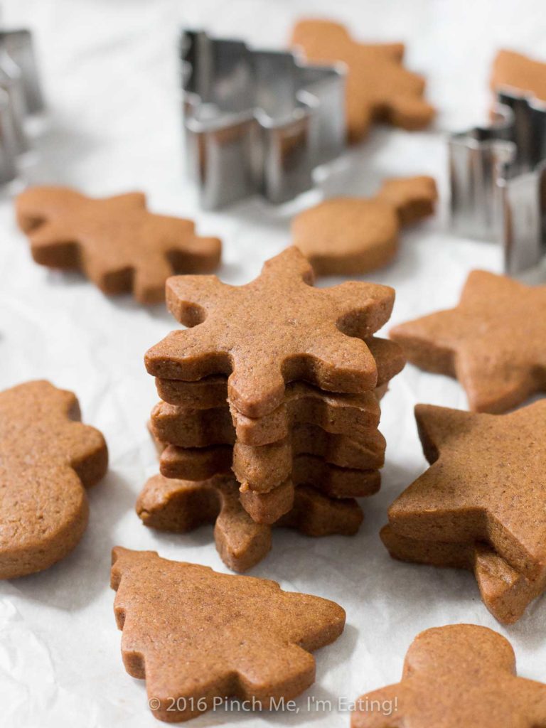 Chewy gingerbread snowflakes in a stack, surrounded by other gingerbread cookies and cookie cutters