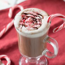 Peppermint mocha in clear mug with candy canes on red napkin