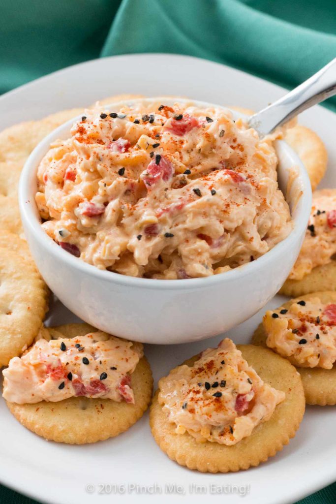 With ample seasonings and just a little kick, creamy Southern pimento cheese is great with everything from crackers or burgers to crab cakes or grits! This cheddar cheese spread also makes a great cold party appetizer dip that doesn't require the oven.