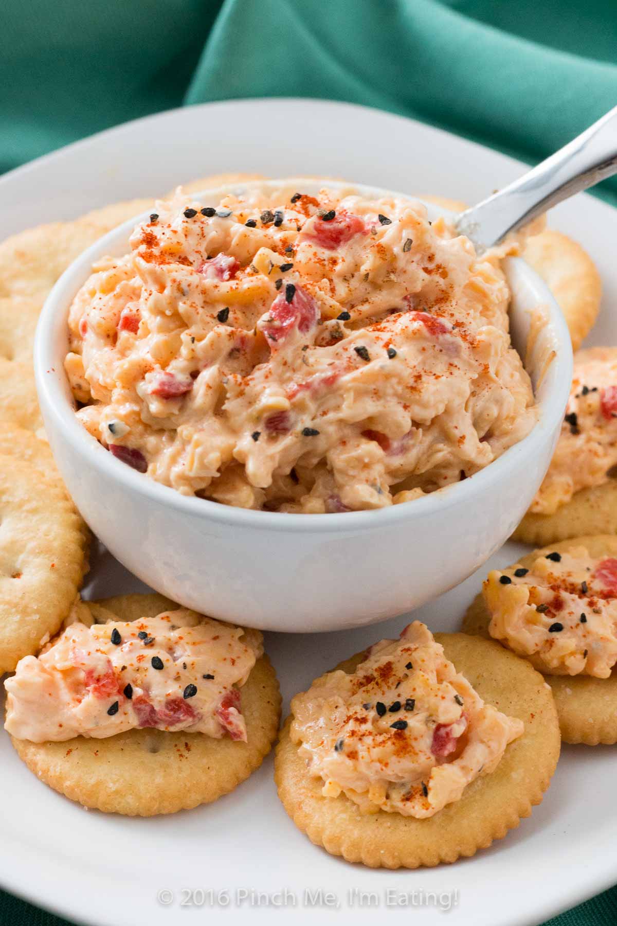 Old-fashioned pimento cheese in a white bowl surrounded by Ritz crackers.