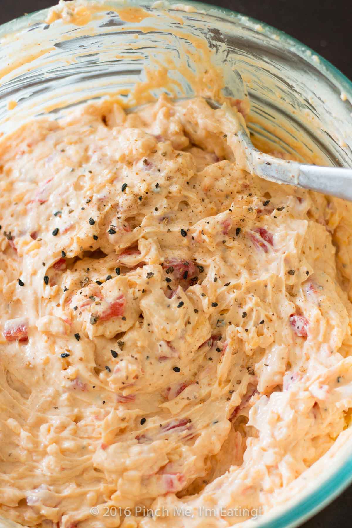 Closeup of creamy Southern pimento cheese sprinkled with a pepper blend.
