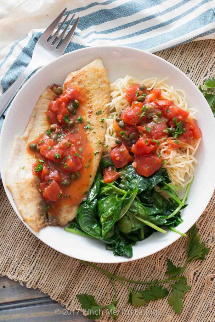 Tilapia with tomatoes and capers is easy to make for a weeknight dinner, healthy, and full of flavor! Serve it with wilted spinach, angel hair pasta, or both. 