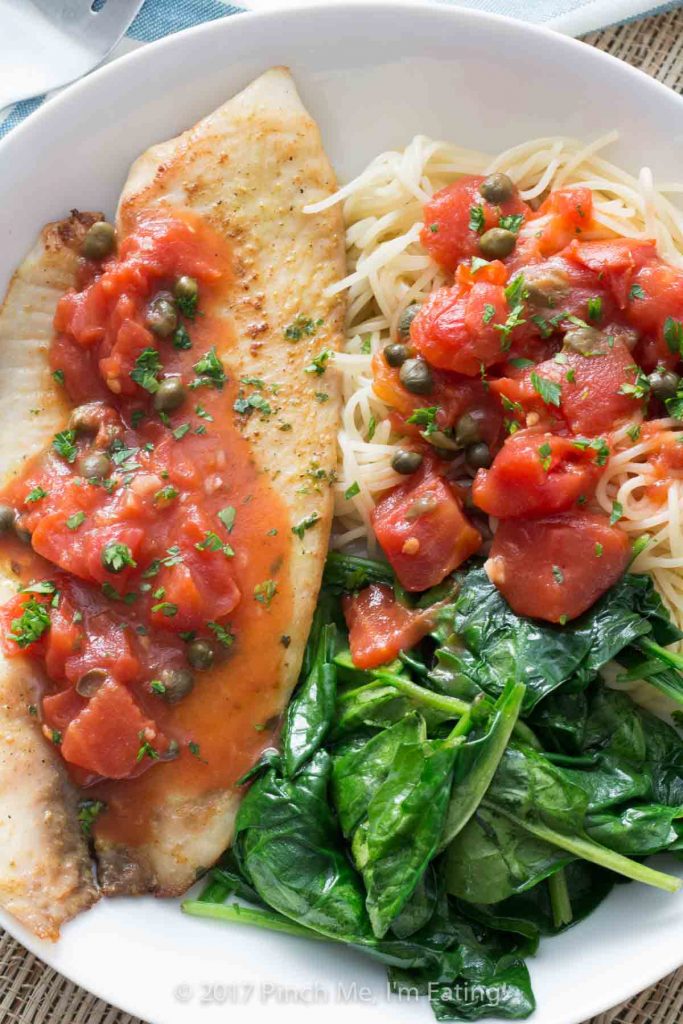 Tilapia with tomatoes and capers is easy to make for a weeknight dinner, healthy, and full of flavor! Serve it with wilted spinach, angel hair pasta, or both.