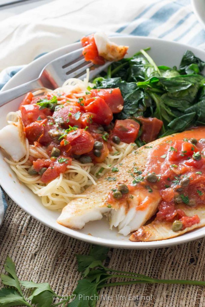 Tilapia with tomatoes and capers is easy to make for a weeknight dinner, healthy, and full of flavor! Serve it with wilted spinach, angel hair pasta, or both.