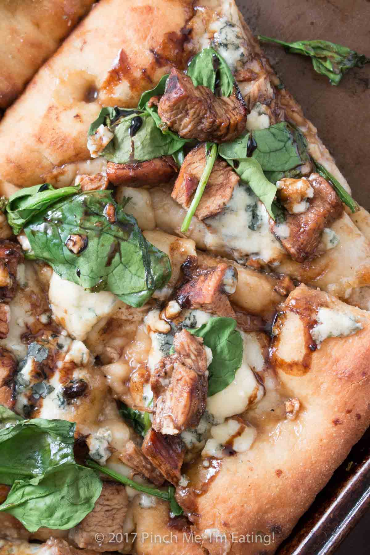 Closeup of balsamic chicken pizza with blue cheese and spinach.
