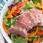 This mixed greens salad with bell peppers and a soy ginger vinaigrette is topped with a rare steak for a light and refreshing spring or summer lunch!