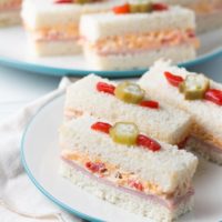 These adorable ham and pimento cheese tea sandwiches would be perfect for a Southern tea party or afternoon tea! And they're topped with the cutest pickled okra garnishes!