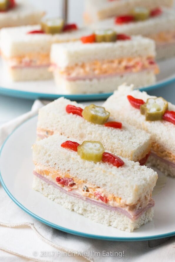 These adorable ham and pimento cheese tea sandwiches would be perfect for a Southern tea party or afternoon tea! And they're topped with the cutest pickled okra garnishes!