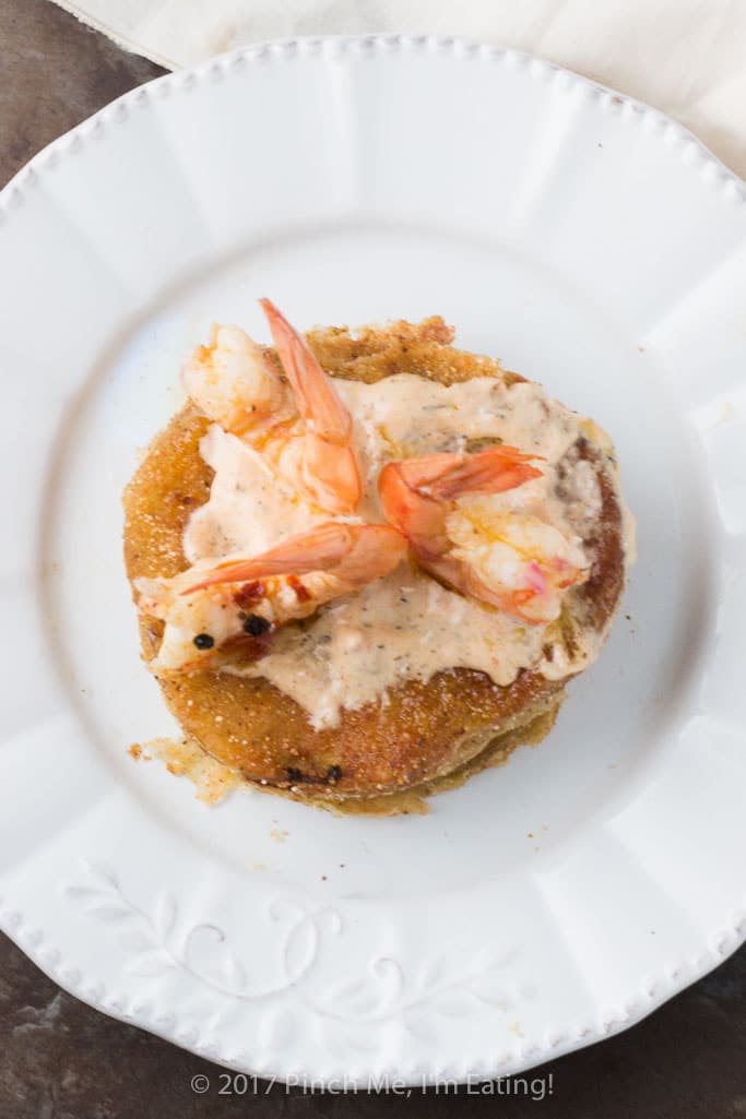 Fried green tomatoes with Cajun remoulade and pickled shrimp on a white dish.