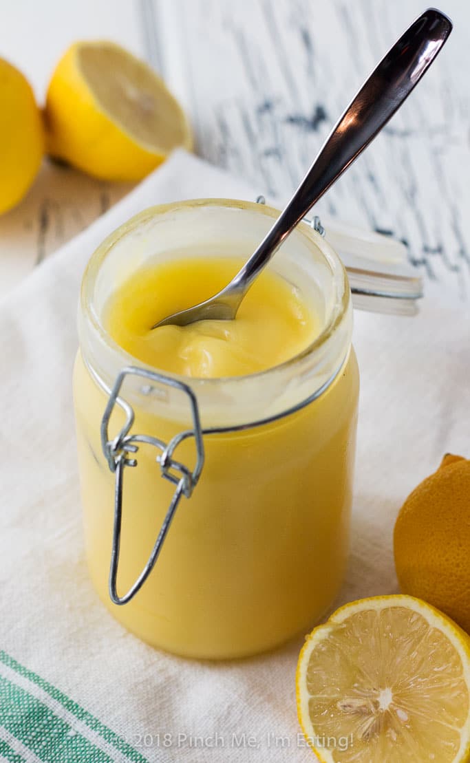 A jar of homemade lemon curd with a spoon.