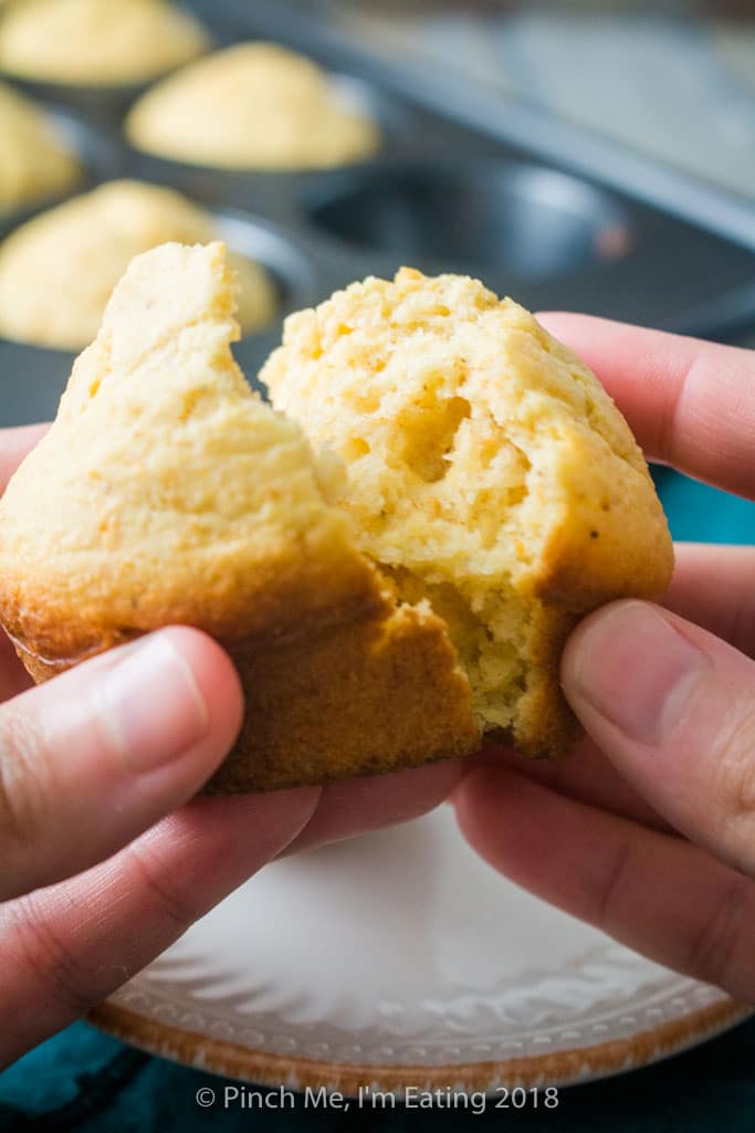 Hands breaking open a moist, airy cornbread muffin