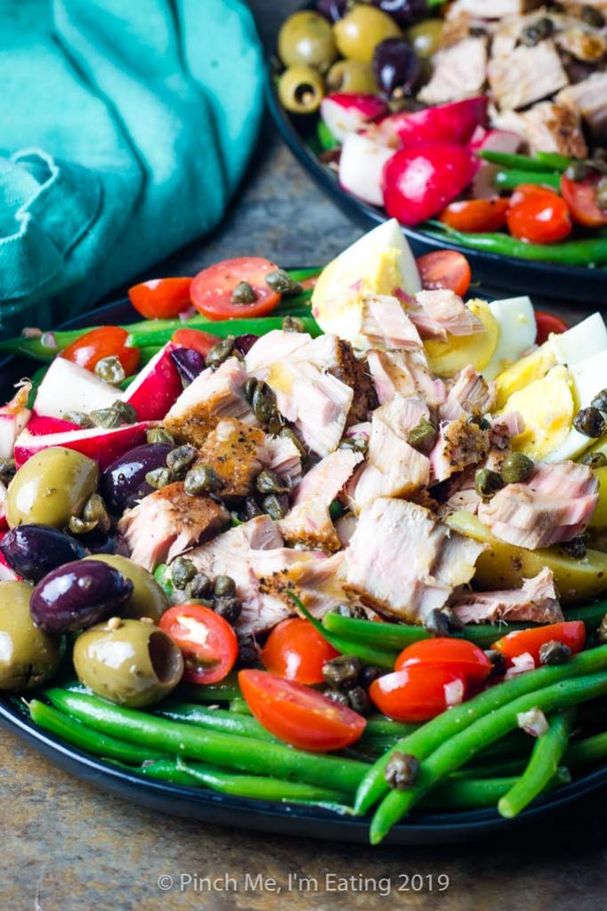 Side view of tuna Nicoise salad with green beans, tomatoes, and olives