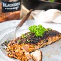 Flaky blackened salmon on a white plate