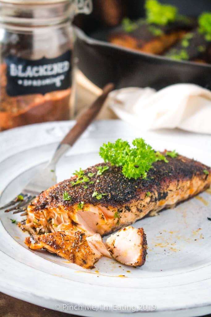 Flaky blackened salmon on a white plate