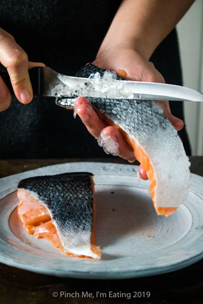 Process shot of taking scales off a salmon fillet