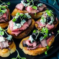 Flank steak crostini appetizers with blue cheese and blueberry caramelized onion jam