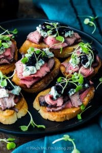 Flank steak crostini appetizers with blue cheese and blueberry caramelized onion jam