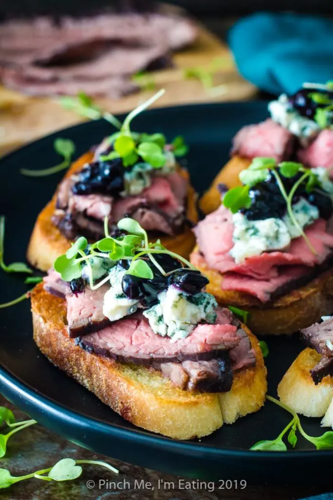 Flank steak crostini appetizers with blue cheese and blueberry caramelized onion jam