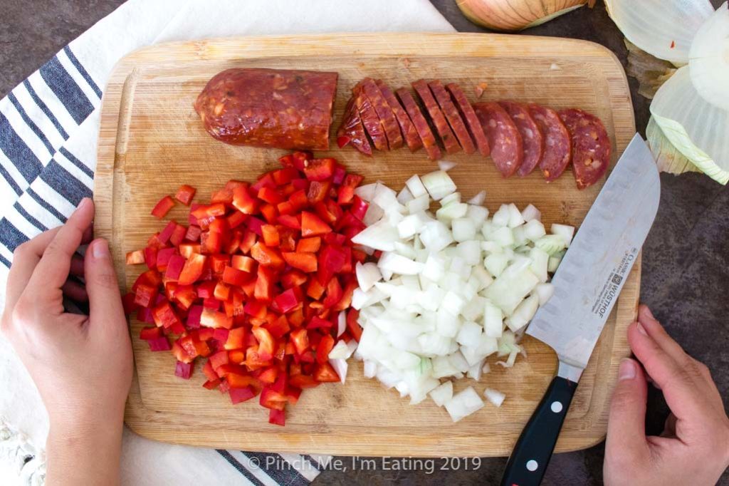 Spanish chorizo, red bell pepper, and onion on a cutting board