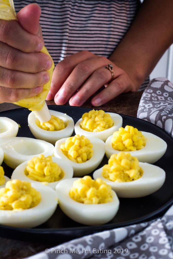 Piping filling into deviled eggs