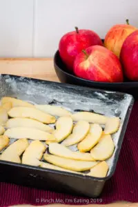 Apple slices arranged on the bottom of a baking pan