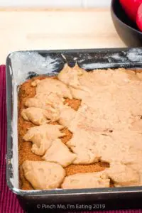 Batter being spread over cinnamon sugar layer for apple coffee cake