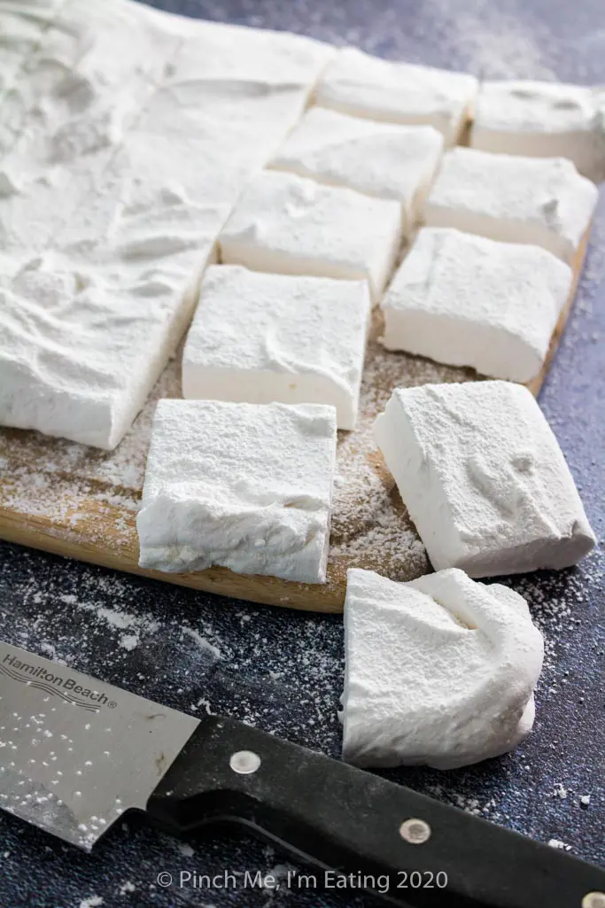 Homemade vanilla marshmallows on a cutting board cut into squares
