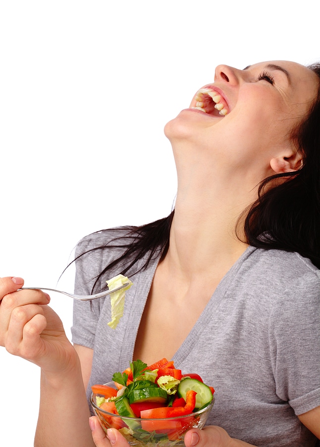 Laughing woman eating tiny salad with no dressing 