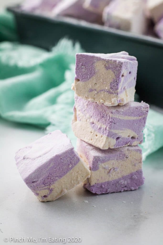A stack of three purple and white swirled homemade Earl Grey marshmallows with one leaning against the side.