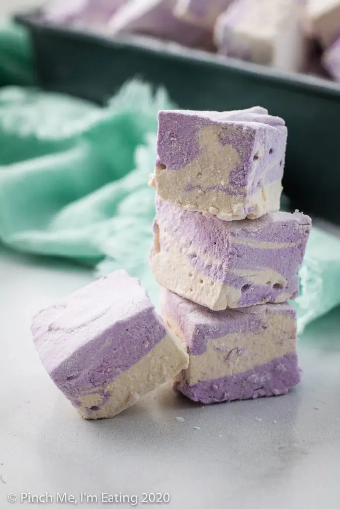 A stack of three purple and white swirled homemade Earl Grey marshmallows with one leaning against the side.